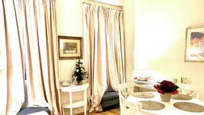 A living room with a sofa, a dining table with chairs, a small Christmas tree, and curtains. - Cozy apartment-Florence old center-Duomo-Uffizi-2 bedrooms-2 bathrooms   (Firenze)