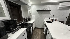 Una cocina compacta equipada con cafetera, estufa, horno y lavabo.