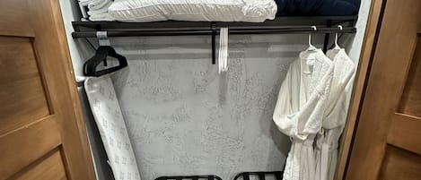 Habitación compacta con literas, un perchero con toallas y una pequeña zona de estar.