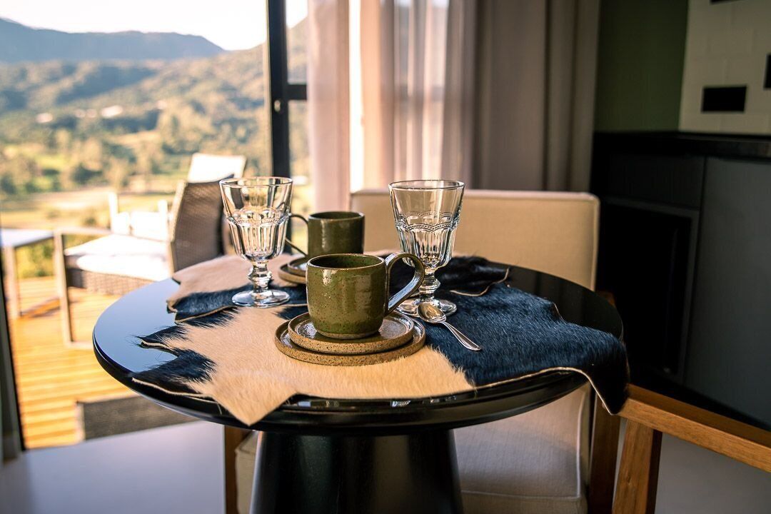 Een eettafel met uitzicht op de omgeving, een groene mok en twee glazen.