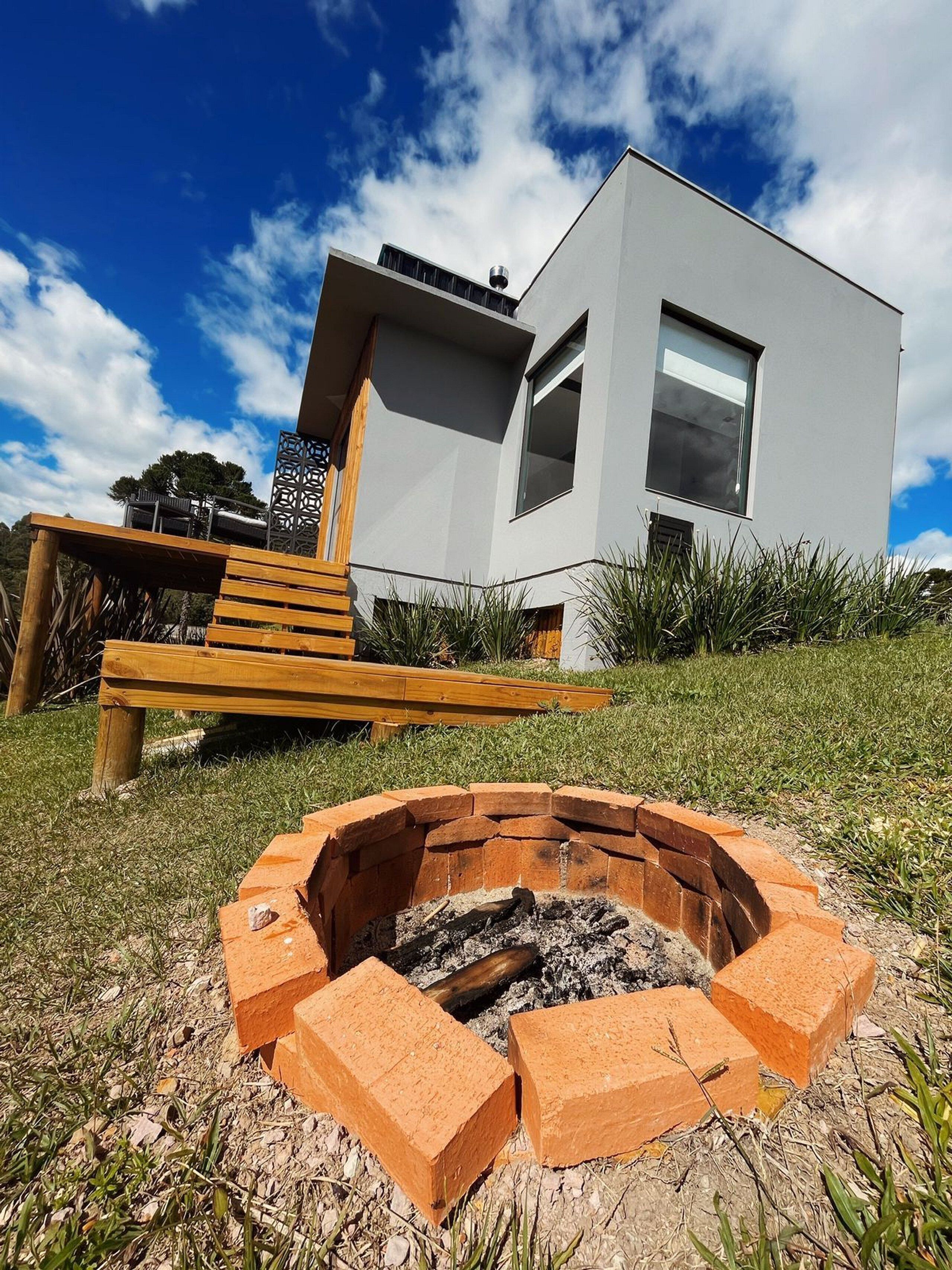 A modern house with a fire pit in the front yard.