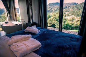 Un dormitorio con una cama grande, una bañera y vistas al campo.