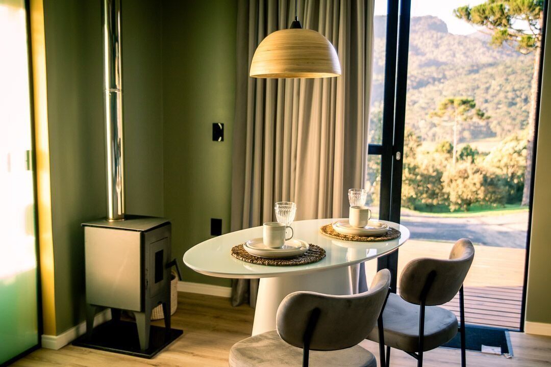 A dining area with a round table, two chairs, a table lamp, and a wood-burning stove.