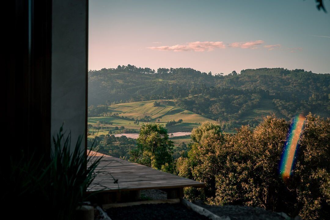 Vista da janela sobre paisagem acidentada com um arco-íris.
