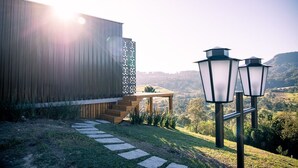 A wooden building with a staircase leading to a deck, surrounded by a stone pathway and three lantern-style lights. - Cabanas Sunset View (Urubici)