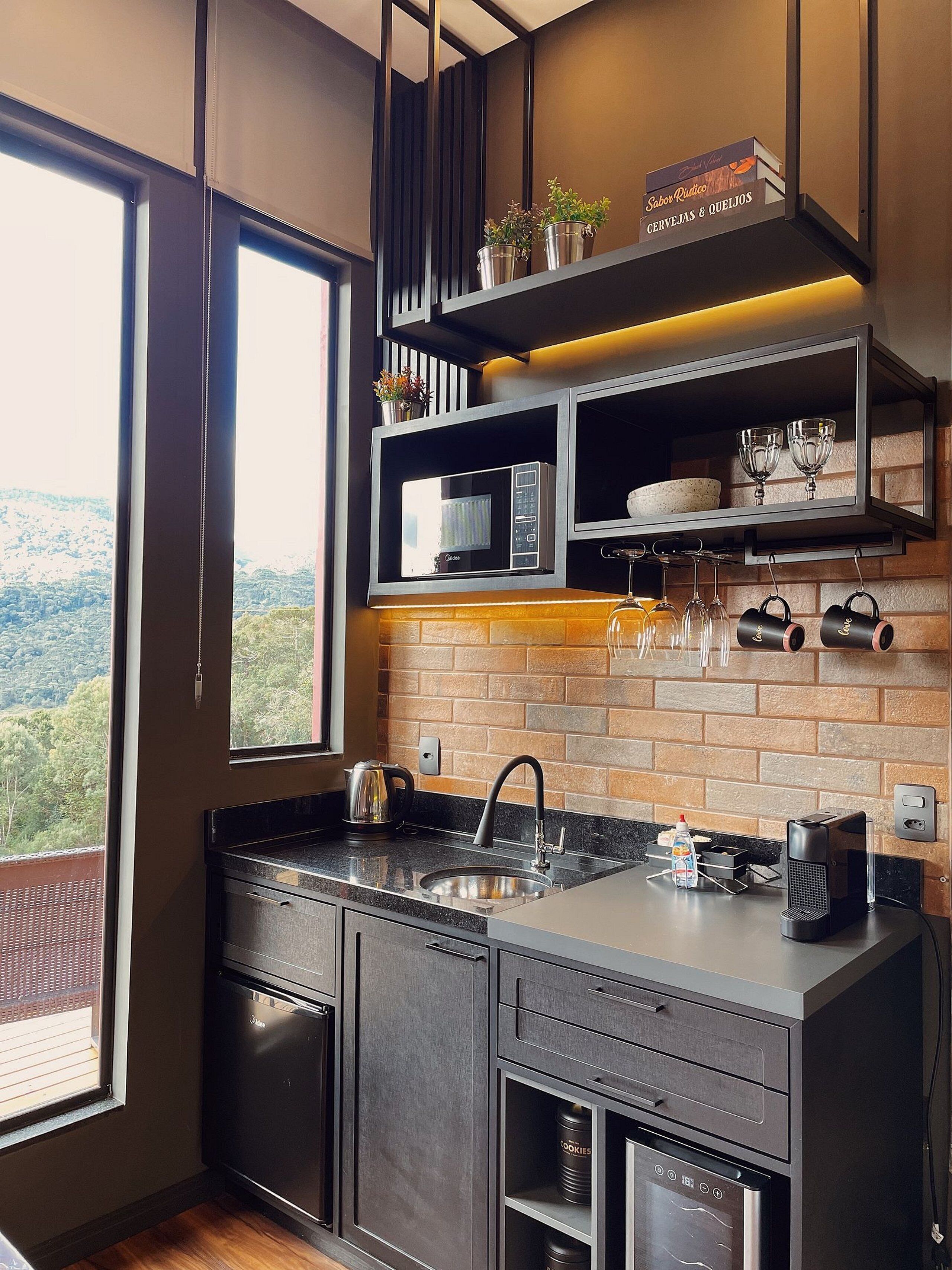 A modern kitchen with a brick backsplash, built-in appliances, and a view of the outdoors.