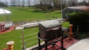 Blick auf eine Rasenfläche mit Grill und kleinem Teich.