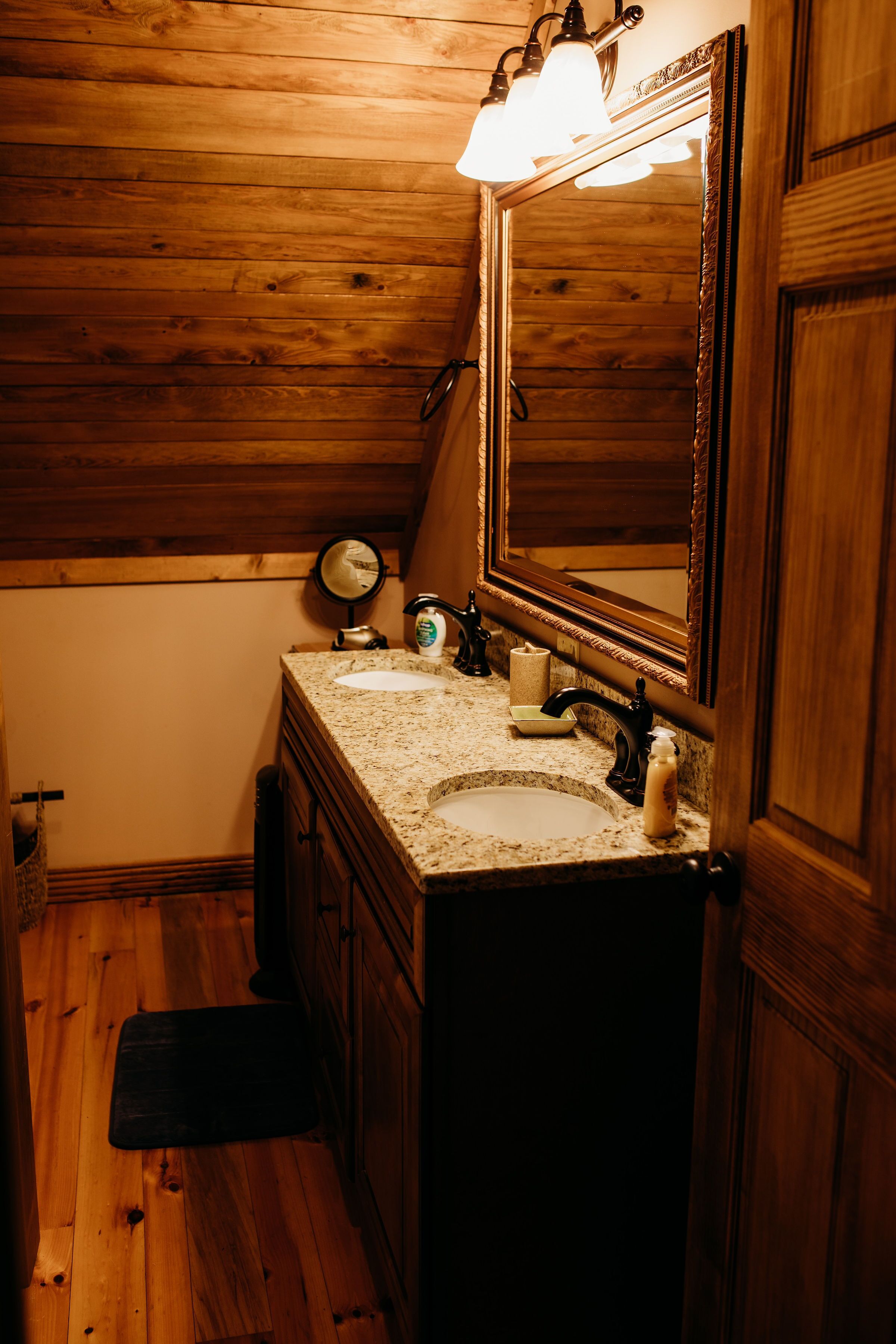 Un baño con paneles de madera, un lavamanos de granito, un espejo y un perchero para toallas.