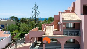A multi-story building with a pink facade, a tiled roof, and balconies. - #132 Velamar 414 by Home Holidays (Albufeira)