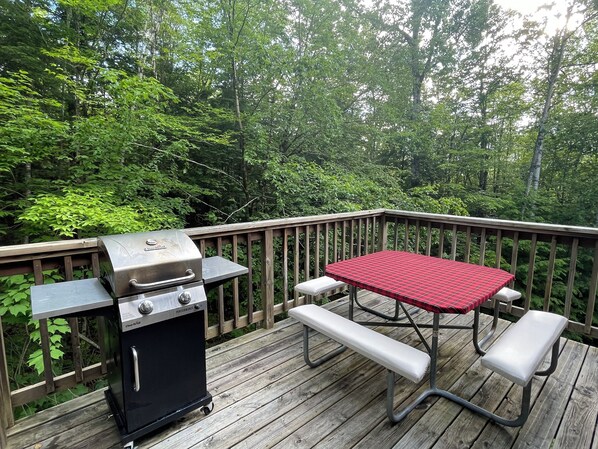 A wooden deck with a barbecue grill and a picnic table with benches. - The Cabin at Crown Ridge, Nestled in the White Mountains of New Hampshire (Conway)
