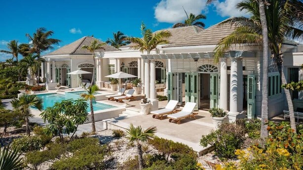 A resort with a pool, lounge chairs, and palm trees. - Beachfront Villa w/ Infinity Pool & Chef (Long Bay)