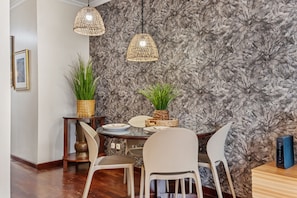 Un comedor con pared de diseño de mármol, dos lámparas colgantes y una mesa dispuesta con platos y sillas.