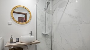 Een badkamer met een witte wastafel, spiegel en douche.