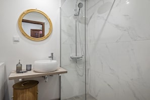 Un baño con lavamanos, espejo y ducha blancos.