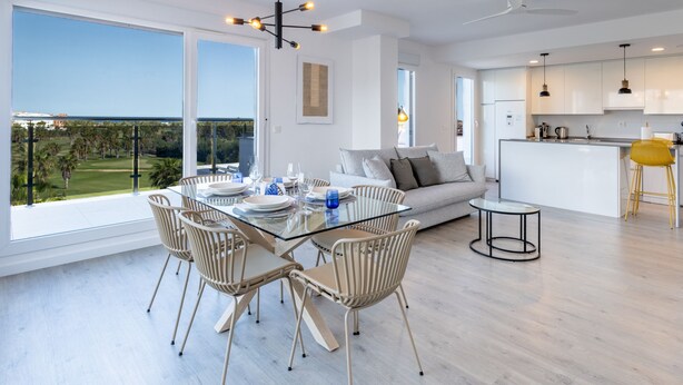 Un espace de vie moderne comprenant une table à manger en verre, un canapé et un coin cuisine.