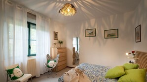 A bedroom with a bed, a chair, a dresser, and a window with curtains. - Pink apartment 4 minutes walk from free beach (San Vincenzo)