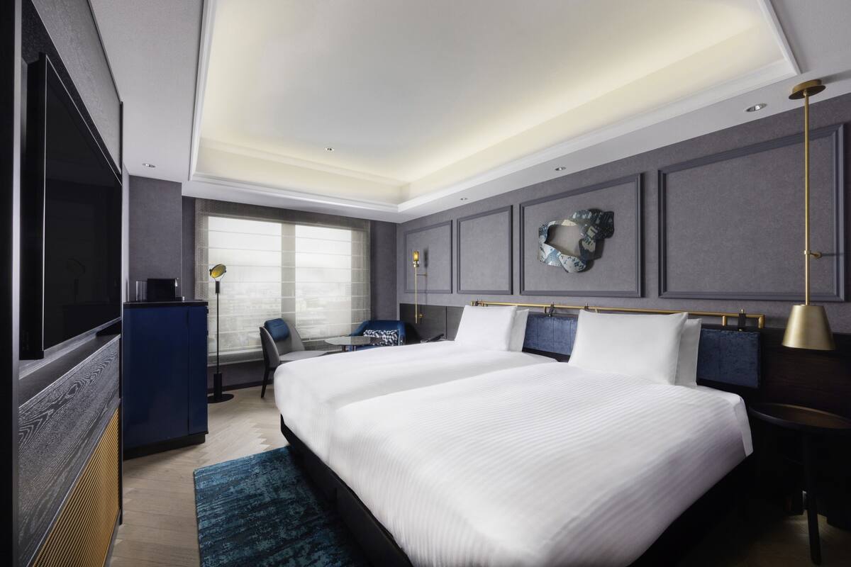 Una habitación de hotel moderna con una cama grande, un escritorio, una silla y un televisor.