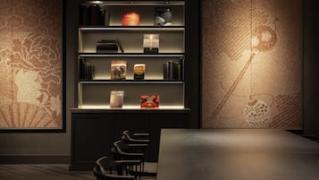 Un interior moderno con una estantería, sillas y una mesa.