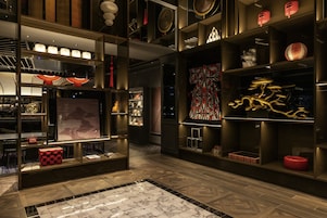 A modern interior with a wooden floor, shelves with decorative items, and a patterned wall.