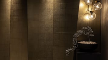 A wall with vertical wooden panels and a bonsai tree on a pedestal.