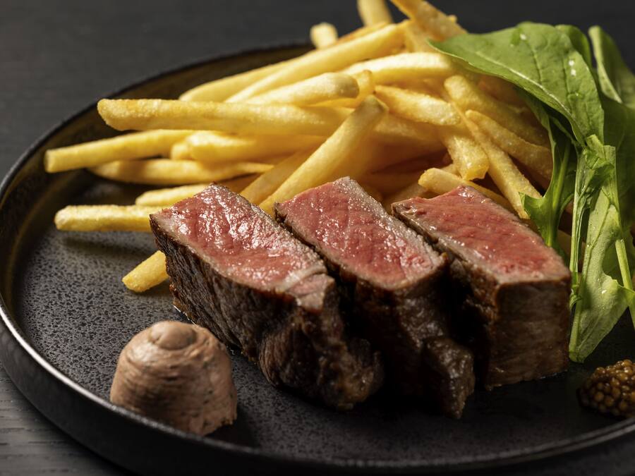 Ein Teller mit Steak, Pommes, Gemüse und Pilzen.