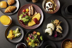 A variety of dishes including croissants, sausages, rice, and a salad, arranged on plates.