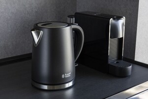 Una cocina moderna con tetera y cafetera sobre una encimera oscura.