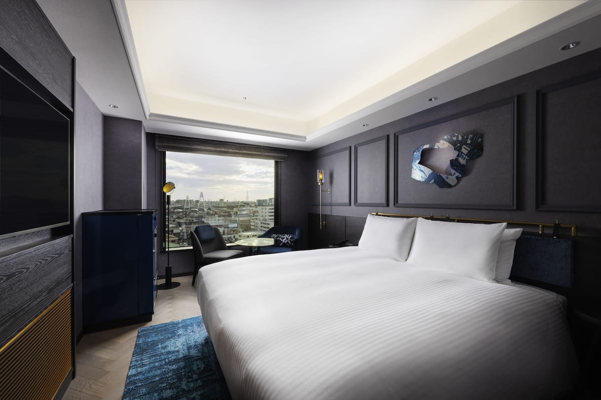 Una habitación de hotel moderna con una cama grande, un escritorio y vistas a la ciudad.