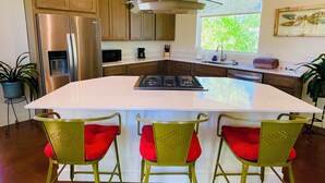 A modern kitchen with a central island, stainless steel appliances, and wooden cabinets.