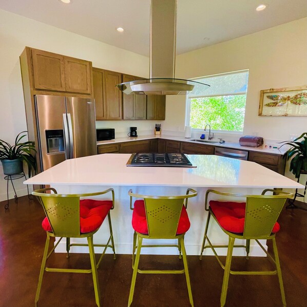 Una cocina moderna con una isla central, electrodomésticos de acero inoxidable y armarios de madera.