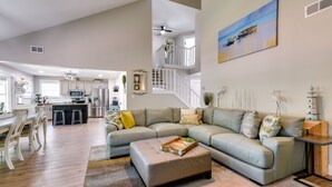 A spacious living room with a sectional sofa, a wooden coffee table, and a dining area with a wooden table and chairs. - Charming Coastal Home: 6 Mi to Choctawhatchee Bay! (Niceville)