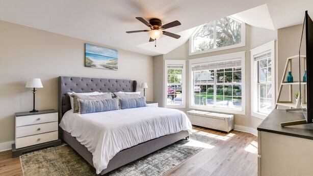 A bedroom with a large bed, a ceiling fan, a window with blinds, and a view of the outside. - Charming Coastal Home: 6 Mi to Choctawhatchee Bay! (Niceville)