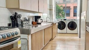 A compact kitchen with a gas stove, coffee maker, and washing machine. - Modern and huge soundproof apt w/AC. Steps to Lleras/Provenza in el Poblado. (Medellín)