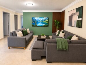 A modern living room with two grey sofas, a coffee table, and a painting of a mountain landscape. - Modern and huge soundproof apt w/AC. Steps to Lleras/Provenza in el Poblado. (Medellín)