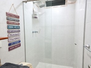 Une douche avec une porte en verre, un porte-serviettes et un mur orné de citations inspirantes.