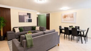 A modern living room with a sectional sofa, dining table, chairs, and artwork on the walls. - Modern and huge soundproof apt w/AC. Steps to Lleras/Provenza in el Poblado. (Medellín)