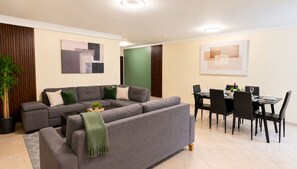 A modern living room with a sectional sofa, dining table, chairs, and artwork on the walls. - Modern and huge soundproof apt w/AC. Steps to Lleras/Provenza in el Poblado. (Medellín)