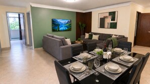 A dining area with a table set for six, a sofa, and a painting on the wall. - Modern and huge soundproof apt w/AC. Steps to Lleras/Provenza in el Poblado. (Medellín)