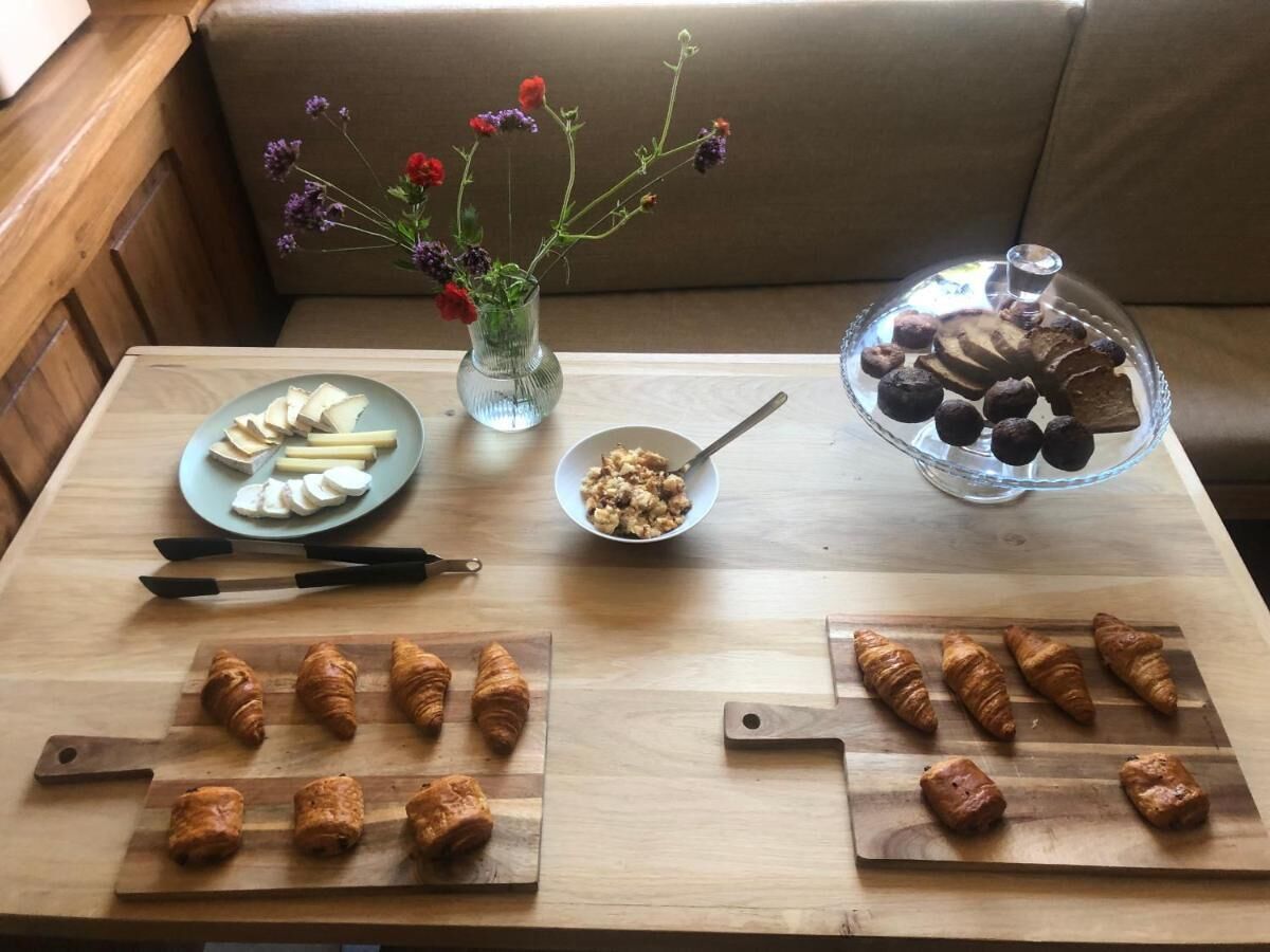 Una mesa de madera con alimentos, un jarrón con flores y una vitrina con pasteles.