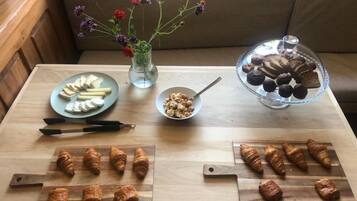 Una mesa de madera con alimentos, un jarrón con flores y una vitrina con pasteles.