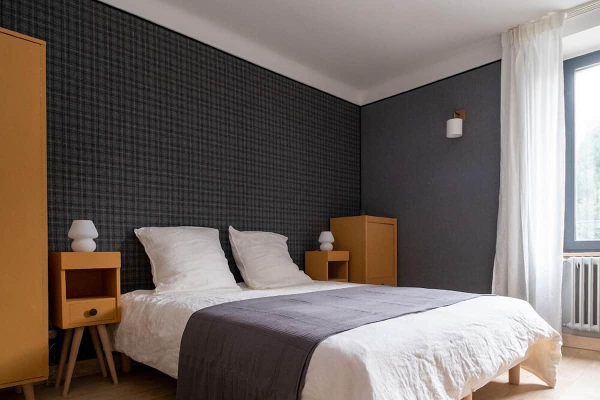 Un dormitorio moderno con una cama grande, mesitas de noche de madera y una pared oscura con textura.