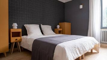Une chambre moderne avec un grand lit, des tables de chevet en bois et un mur à texture sombre.