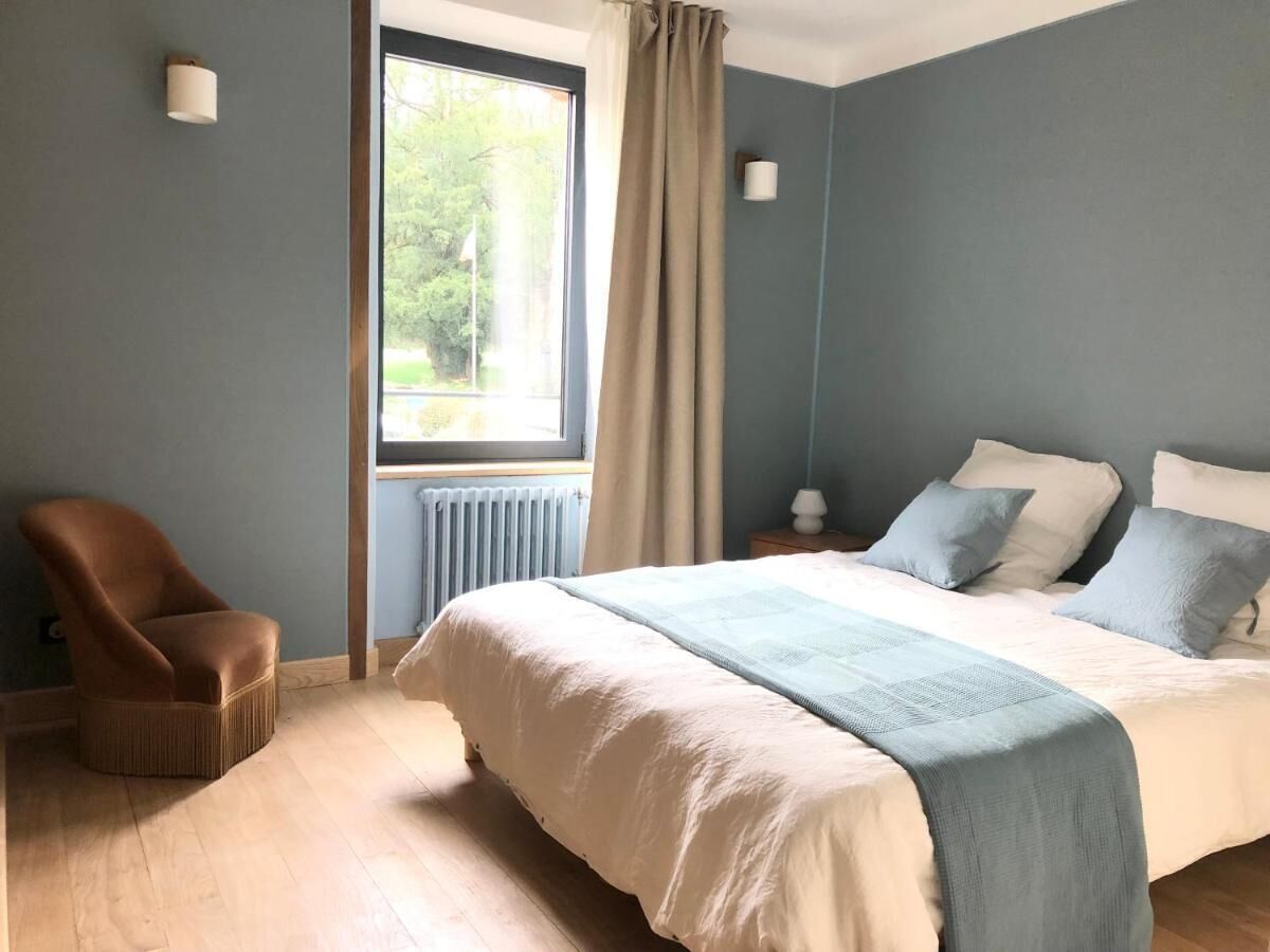 Un dormitorio con una cama grande, una silla, una ventana con cortinas y un radiador.