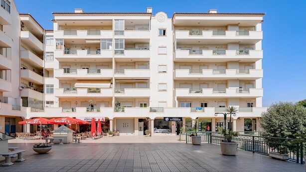 A multi-story hotel with balconies, a central courtyard with outdoor seating, and a sign for 'O Carega'. - Comfy 4BDR Apartment in Portimão by LovelyStay (Portimão)