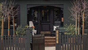 Ein dunkelgraues Haus mit Veranda, Holzzaun und Briefkasten.