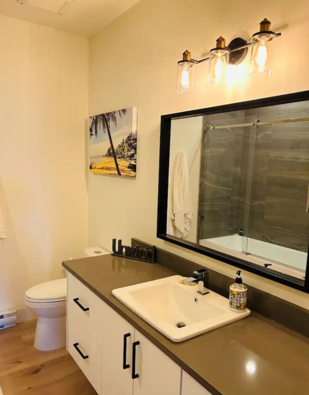 A bathroom with a large mirror, a sink, and a shower.