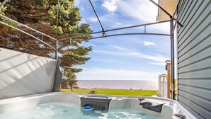 A hot tub with a view of the sea, surrounded by a metal frame and a white wall.