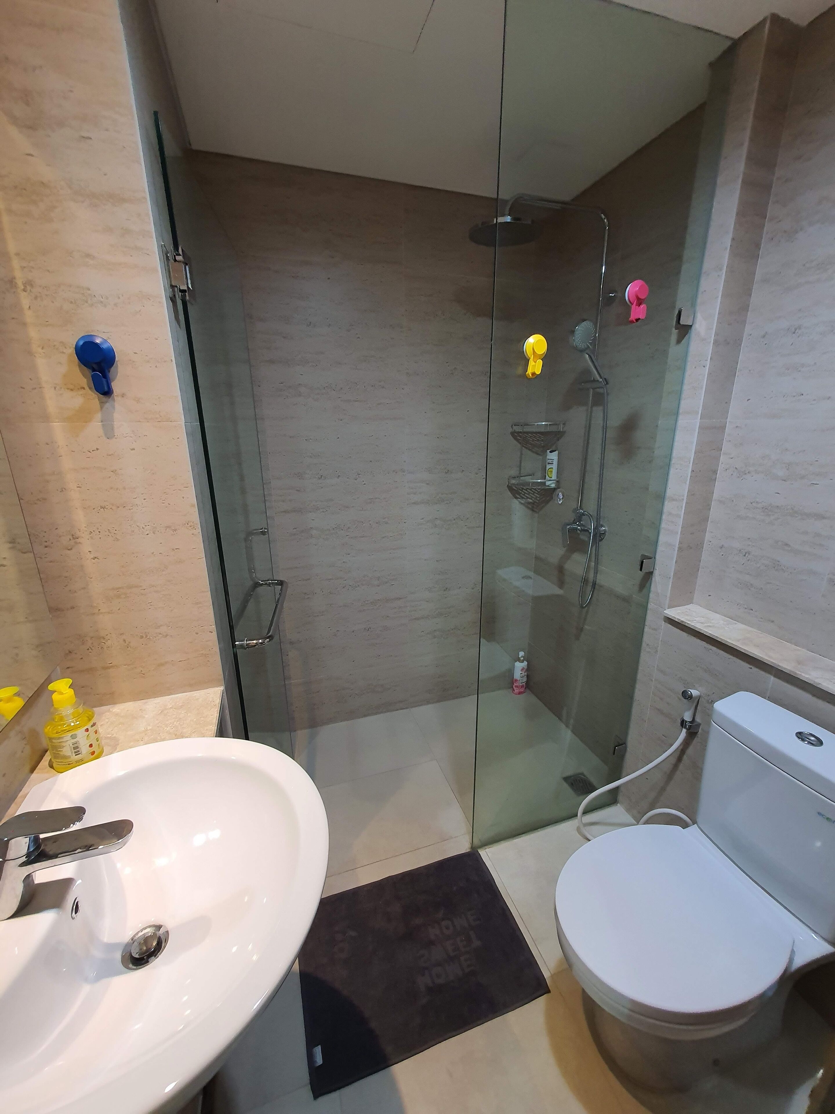 A modern bathroom with a glass-enclosed shower, a white sink, and a toilet.