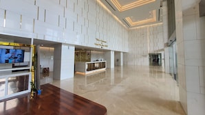 Eine großzügige Lobby mit modernem Design, mit poliertem Marmorboden, einer Rezeption und einem großen Flachbildfernseher.