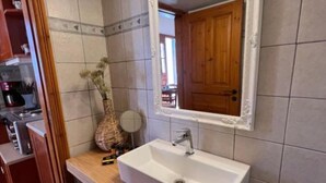 Een badkamer met een witte wastafel, een houten opbergmeubel en een spiegel.